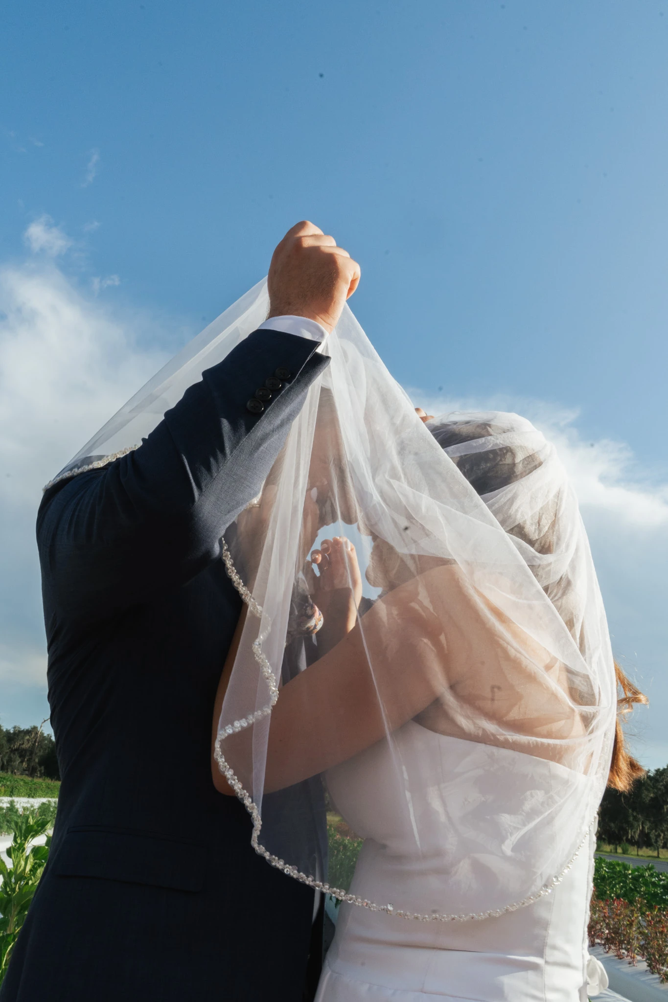 The groom holds the veil up over them both